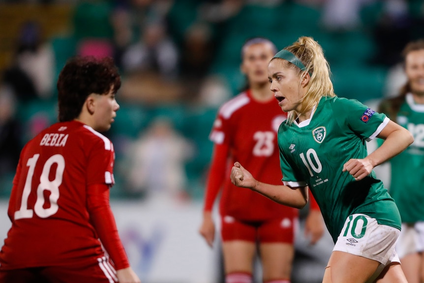 An irish women's footballer pumps her fist in celebration as she runs away from goal.