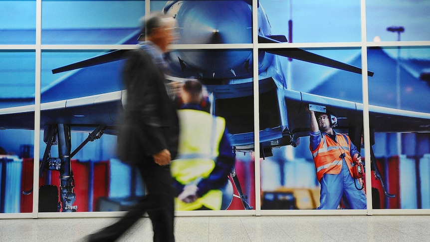 Man walks past Eurofighter jet at arms fair in London