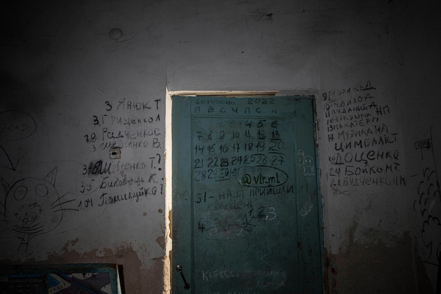 A doorway covered in Ukrainian words, scrawled with a black marker