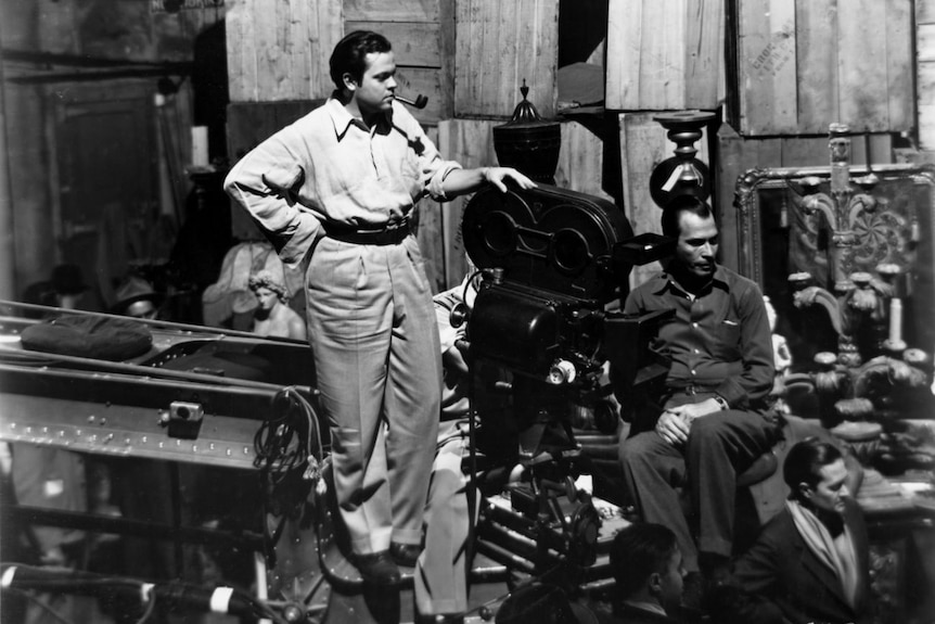 A black and white photo of director Orson Welles standing on a camera boom on the set of Citizen Kane in 1941.