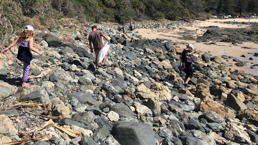 People walking along rocks near a beach