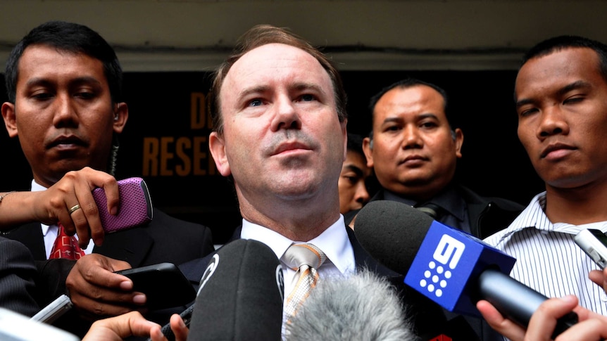 Greg Moriarty speaks to the media, surrounded by Indonesian officials