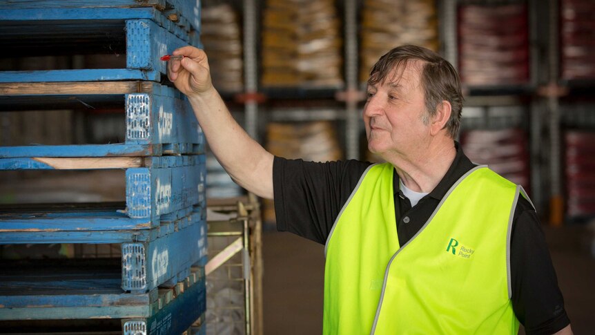 Lawrence Waterman counts a stack of Chep pallets inside a warehouse.
