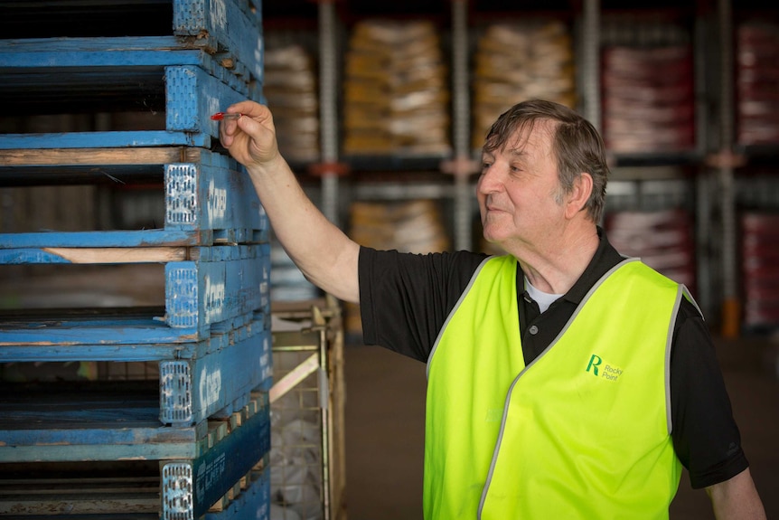 Lawrence Waterman counts a stack of Chep pallets inside a warehouse.