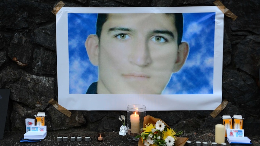 A photograph of Reza Barati sits above candles and flowers in a small shrine display.