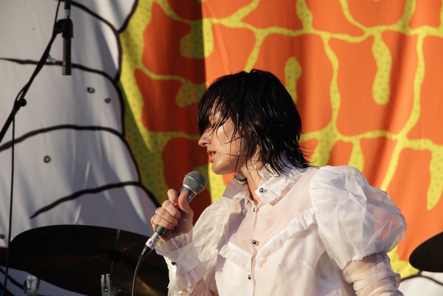 Lead singer of the Preatures on stage, close up shot, her head is turned to the left and she's singing into the microphone.