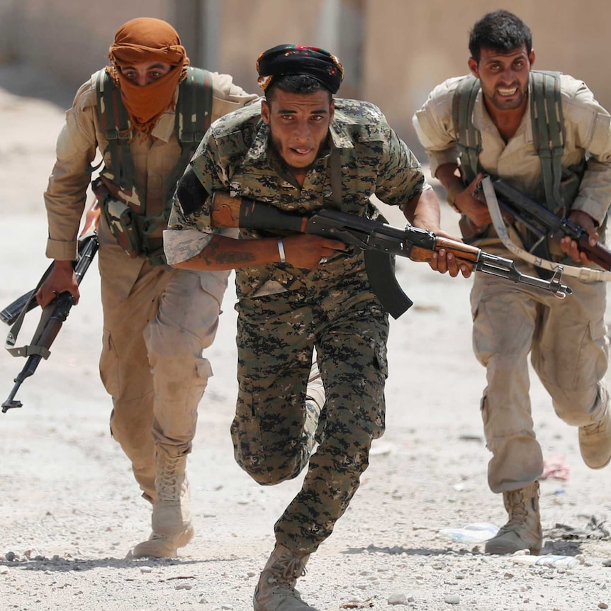 A group of mean in military uniforms run with machine guns in hand, hunched over as they duck for cover.