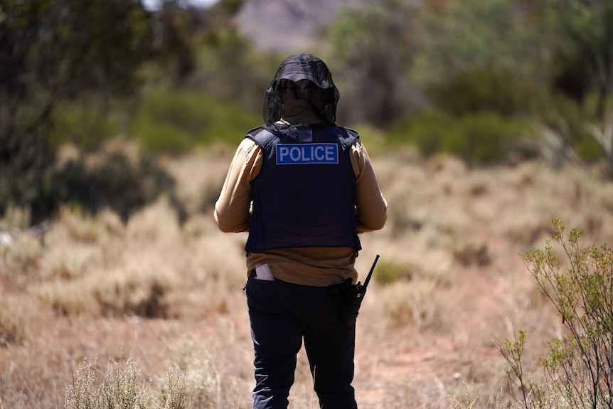 A police officer in a vest standing in a paddock