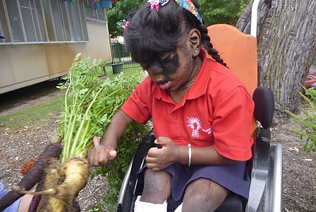 A girl dressed in a school uniform in a wheelchair.