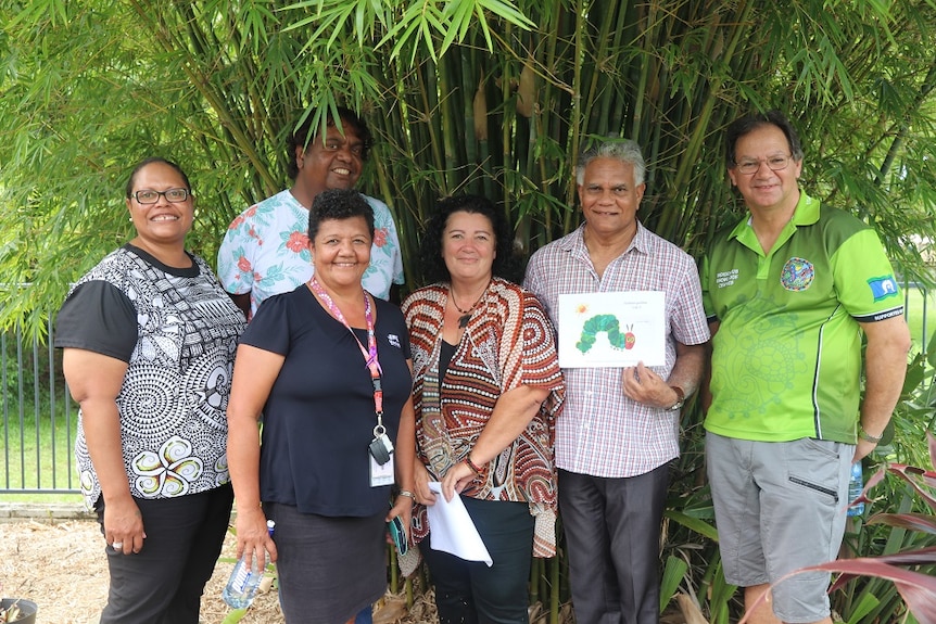 Six people holding up a copy of The Very Hungry Caterpillar