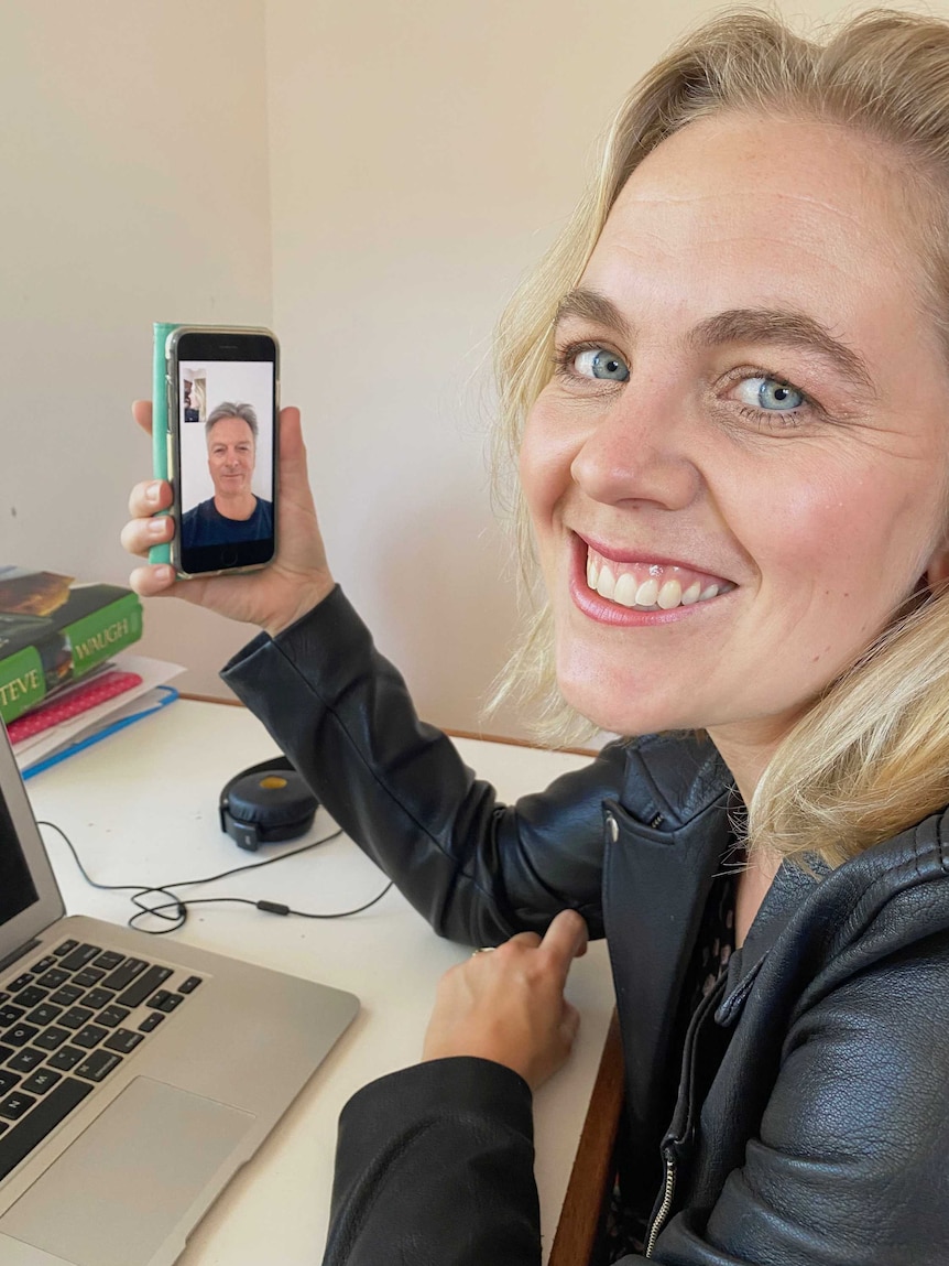 Minchin holding smartphone with Waugh on screen.