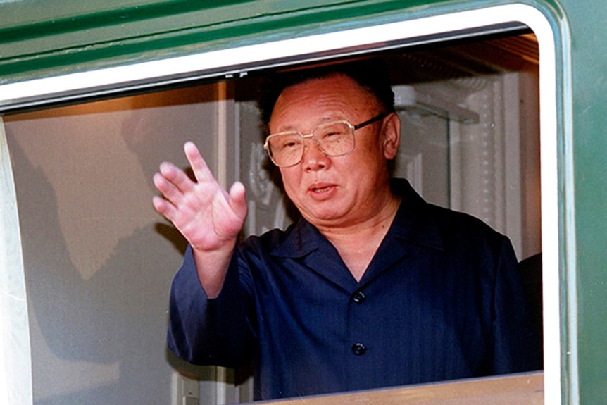 Former North Korean leader Kim Jong-il waves from the open window of his armoured train