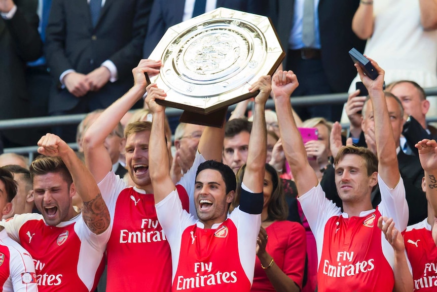 Mikel Arteta raises the Community Shield as his Arsenal teammates celebrate on the dais around him