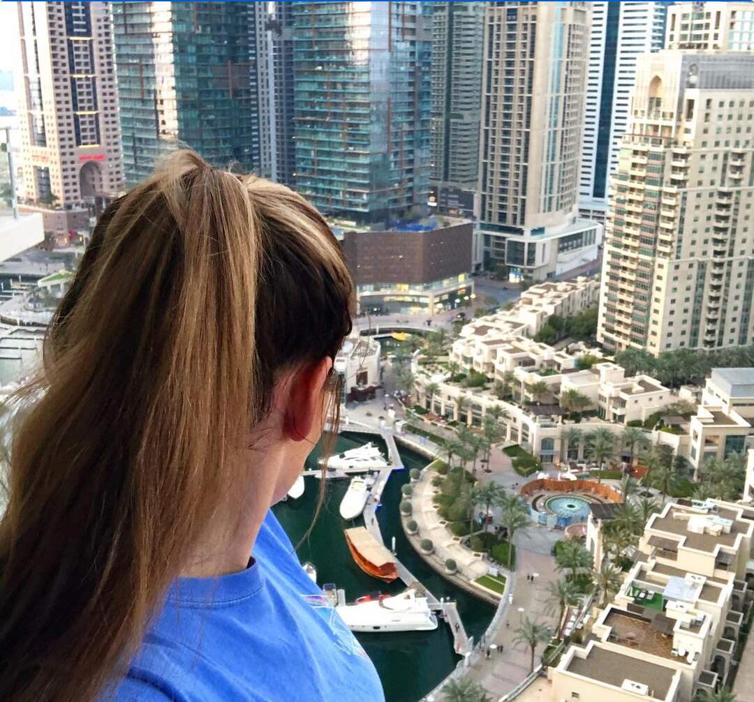 Woman has back to camera overlooks Dubai Marina. 