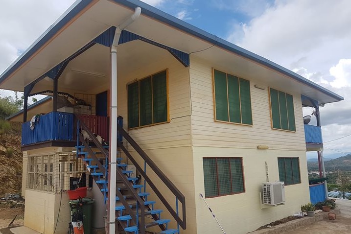 The exterior of a double-storey house with a mountain view.