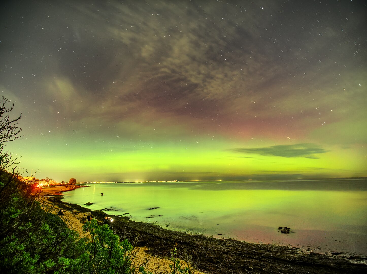 Um céu verde com vista para uma praia à noite
