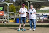 man with cap and glasses stands next to man with grey hair holding lawn bowls balls
