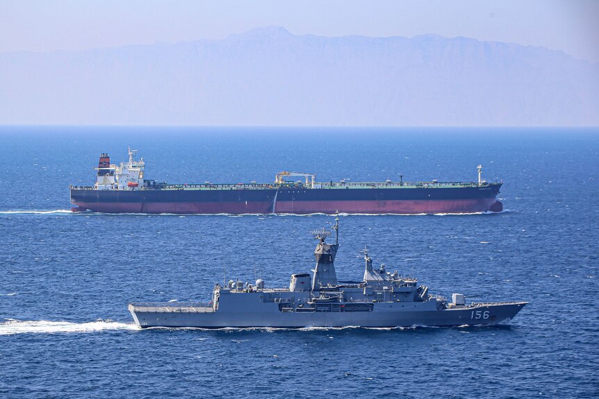 Two Australian navy ships move alongside one another in the ocean