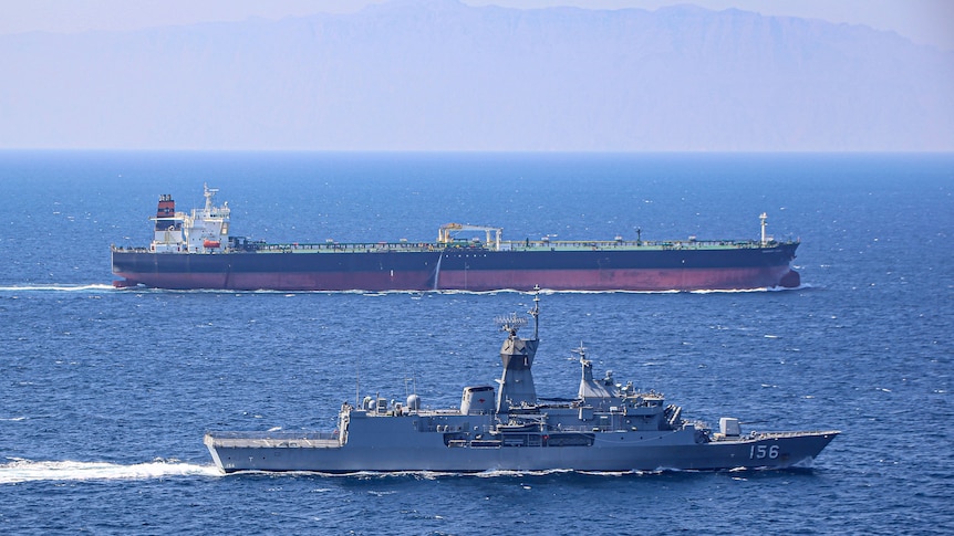 Two Australian navy ships move alongside one another in the ocean