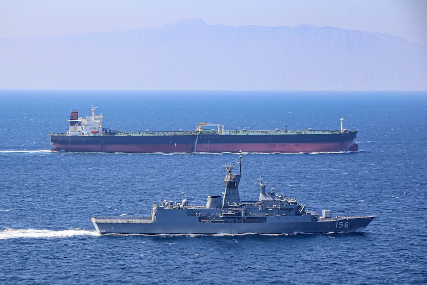 Two Australian navy ships move alongside one another in the ocean