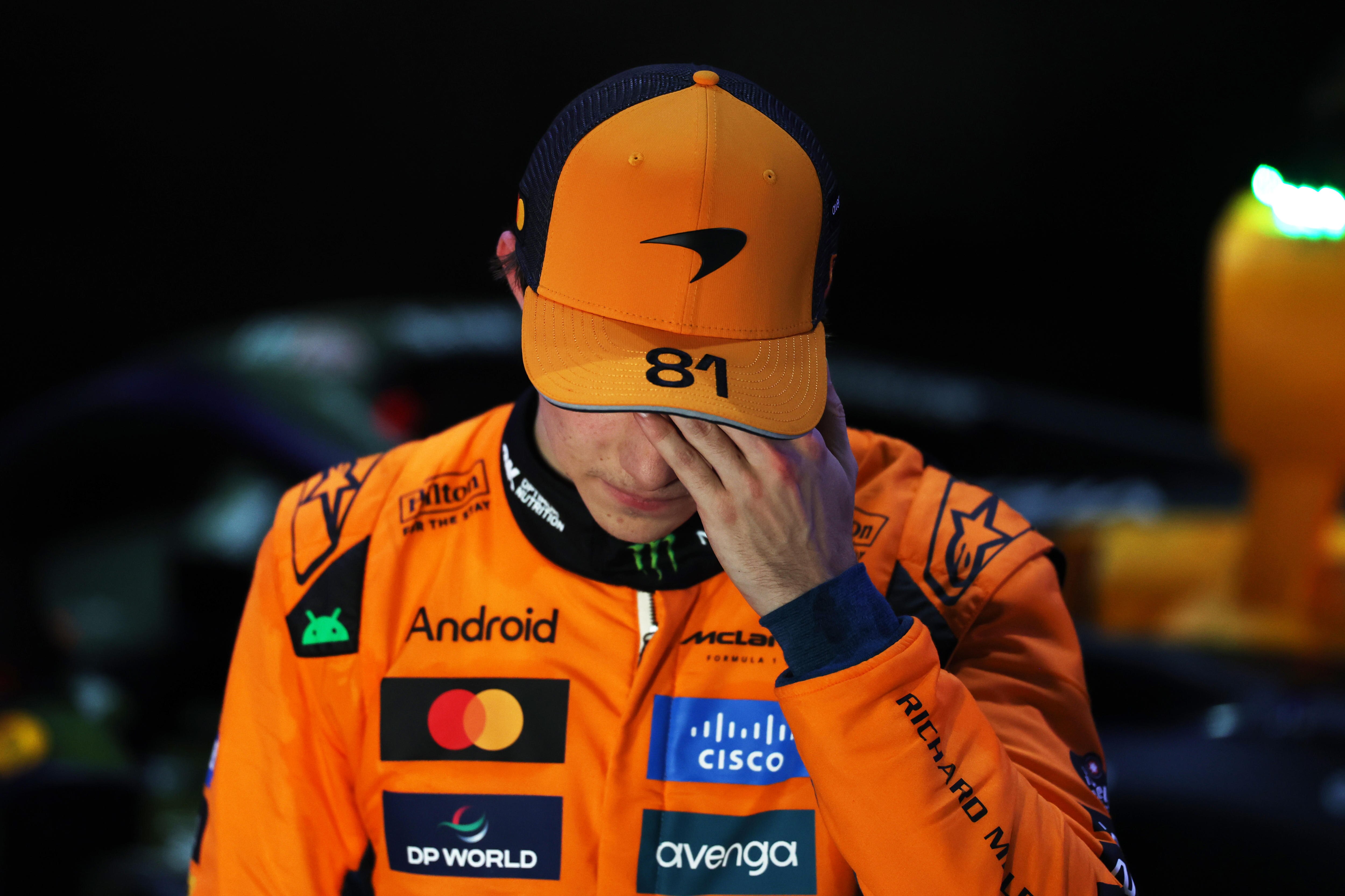 Oscar Piastri con ropa de carreras de F1 se sostiene la cabeza y mira hacia abajo