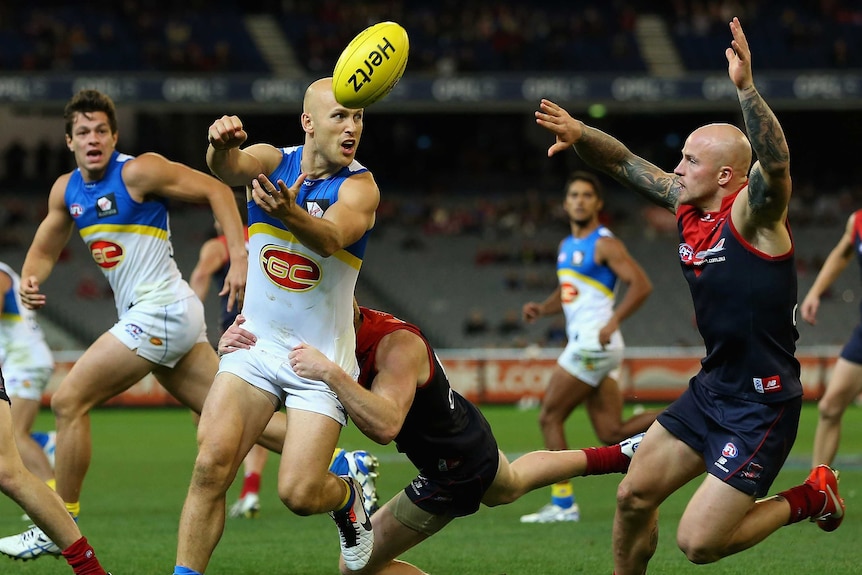 The Suns' Gary Ablett handballs under pressure from the Demons.