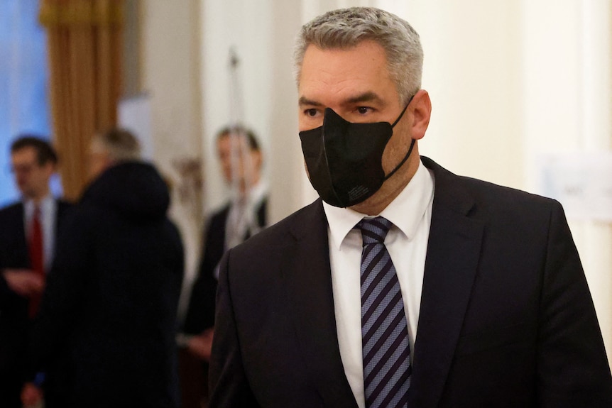 Karl Nehammer wears a black face mask and a suit on his way to meet with Mr Putin,