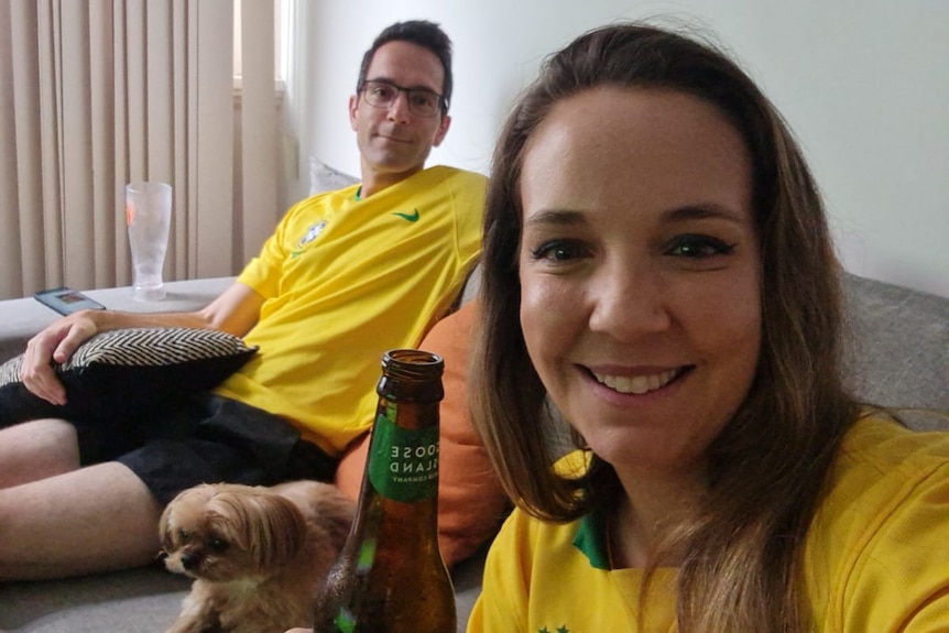 Two Brazilian supporters wearing replica shirts in their lounge room.