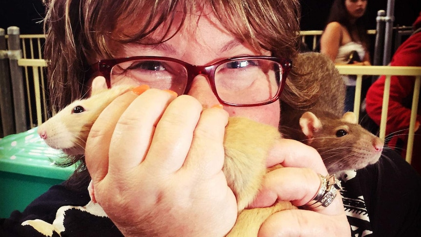 A woman holds up an animal and looks at the camera.