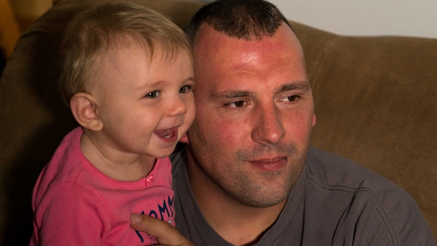 Tommy Wolikow with his 9 month old daughter Annabella smiling at the camera