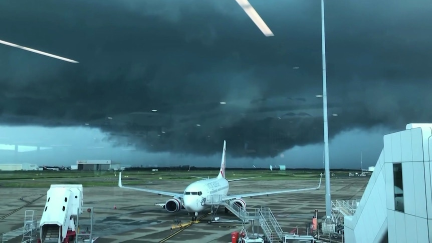 Planes on Brisbane Airport airport tarmac as a storm develops on the horizon