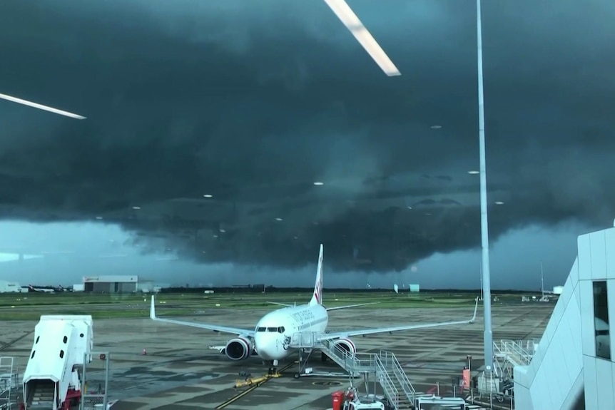 Planes on Brisbane Airport airport tarmac as a storm develops on the horizon