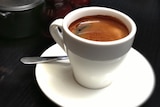 White cup of instant coffee on a saucer with a spoon.