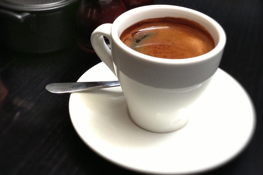 White cup of instant coffee on a saucer with a spoon.