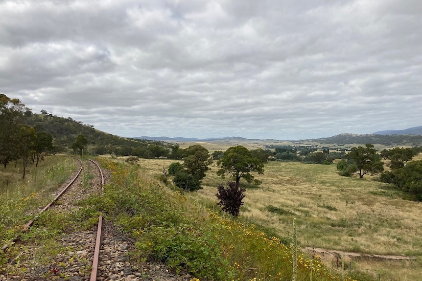 an old railway line overlooking hills with an overcast sky