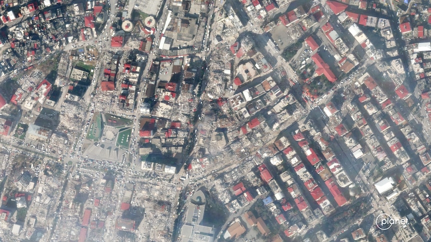 Aerial photo of buildings surrounded by rubble and dust.