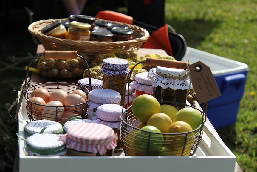 Jams, chutneys and eggs laid out on a table in baskets.