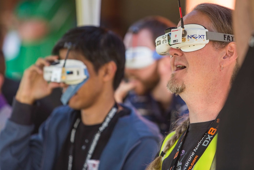 Three men wear goggles over their eyes.