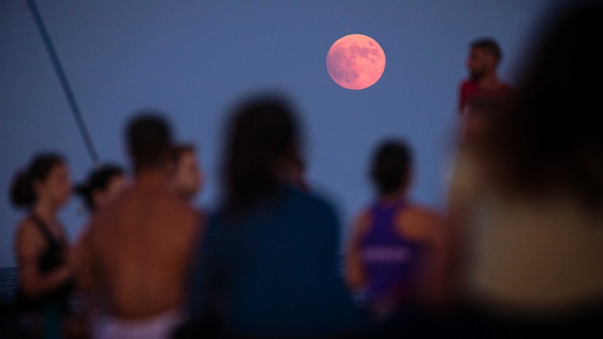 The moon is seen above a yoga class