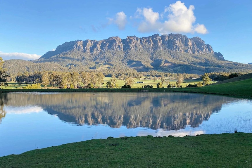 A farm dam with the reflection of a mountain in the background