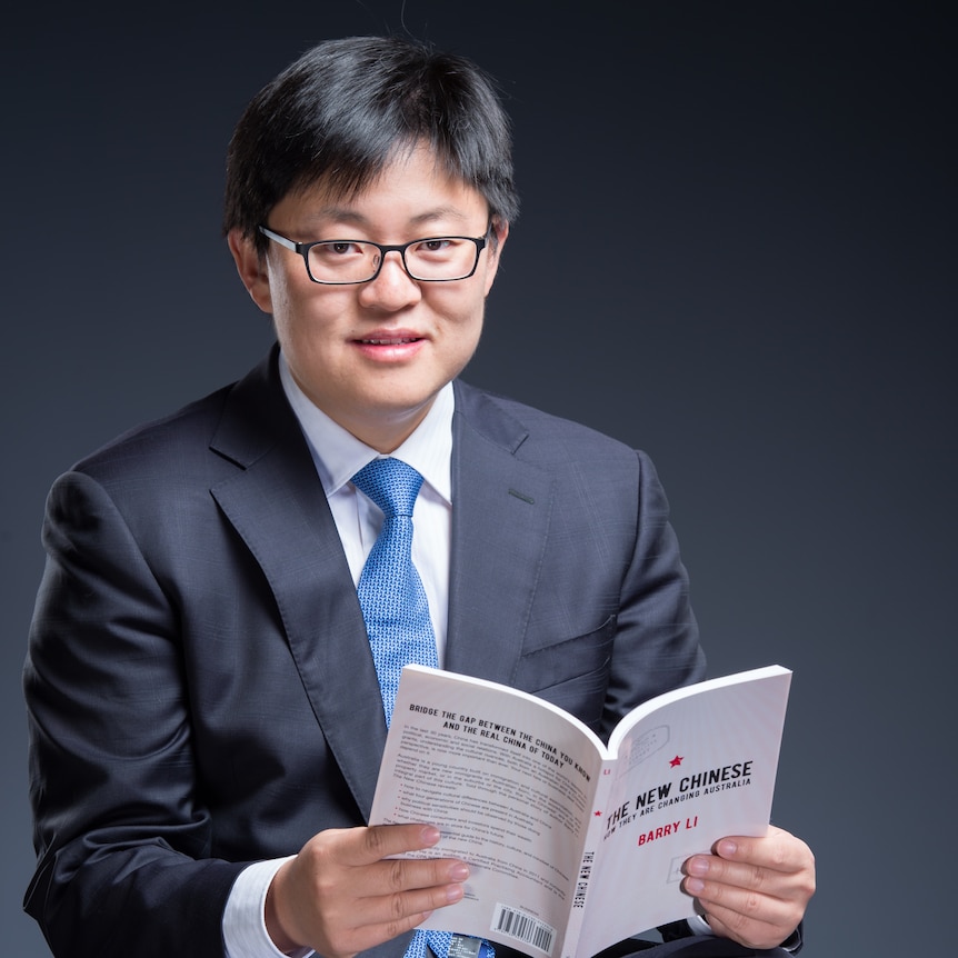 A young Chinese man holds a book. 