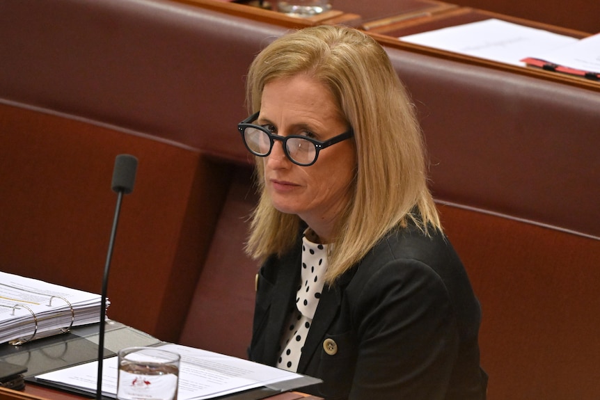 A woman with blonde hair sits in a parliament