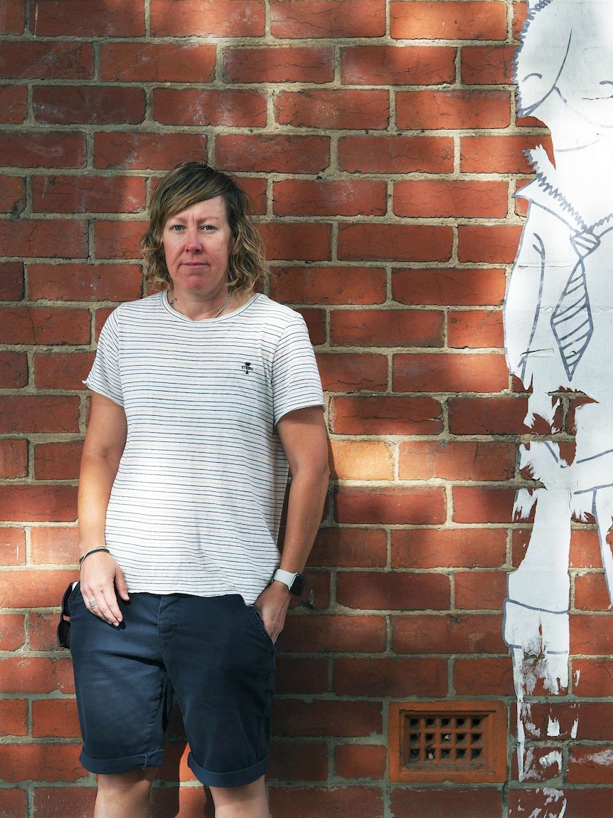 Floorball played Belinda Cameron standing in front of a brick wall.