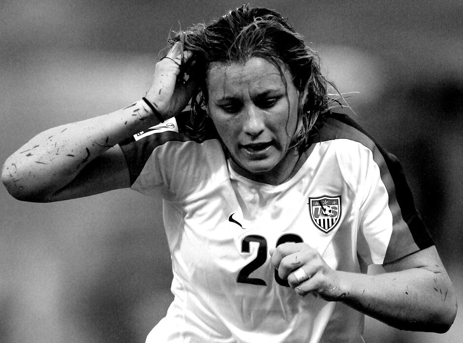 Abby Wambach holds her hand to hear bleeding head on the field.