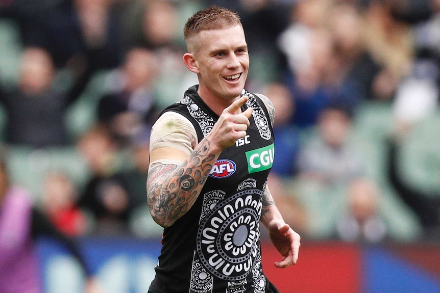 A Collingwood AFL player points with a finger on his right hand during a match against Fremantle in 2019.