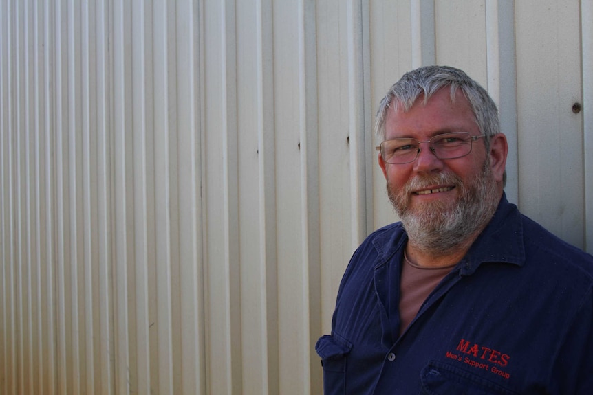 An older, bearded man wearing a dark shirt.