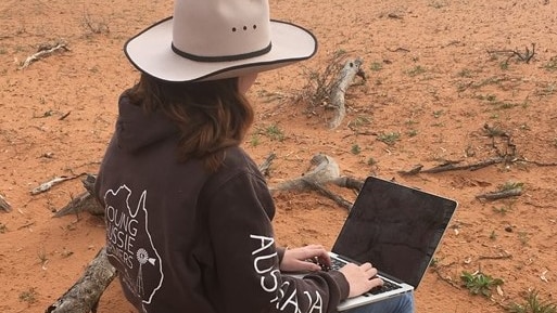 A high-school student with a laptop in the outback