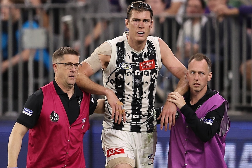 The Magpies' Mason Cox helped from the field injured against the Dockers.