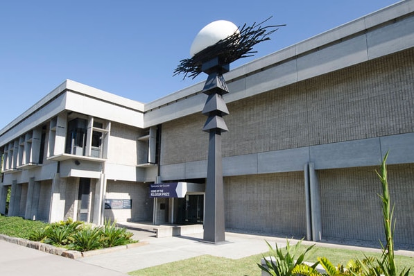 An exterior shot of a concrete gallery building, with a large steel sculpture of a stylised egg in a nest in front.