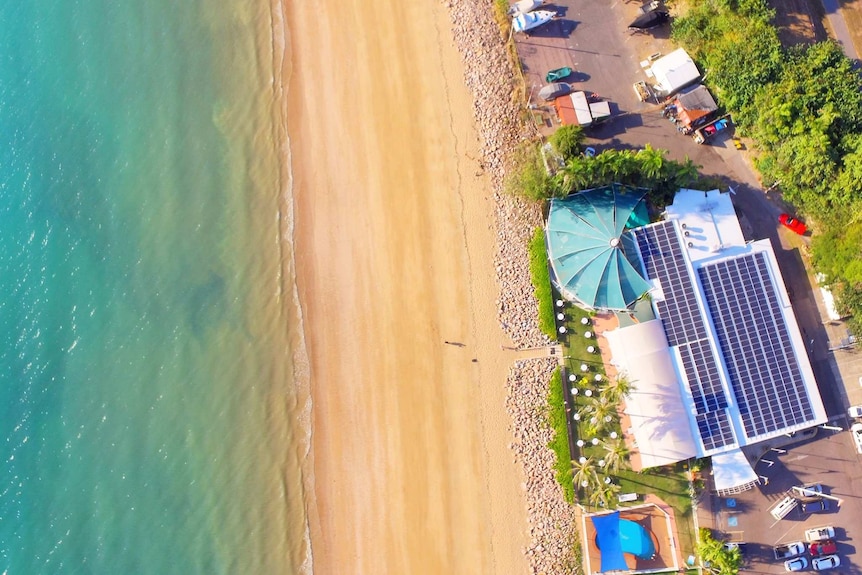 An aerial image of a beachside boat club with a pool in its back courtyard.